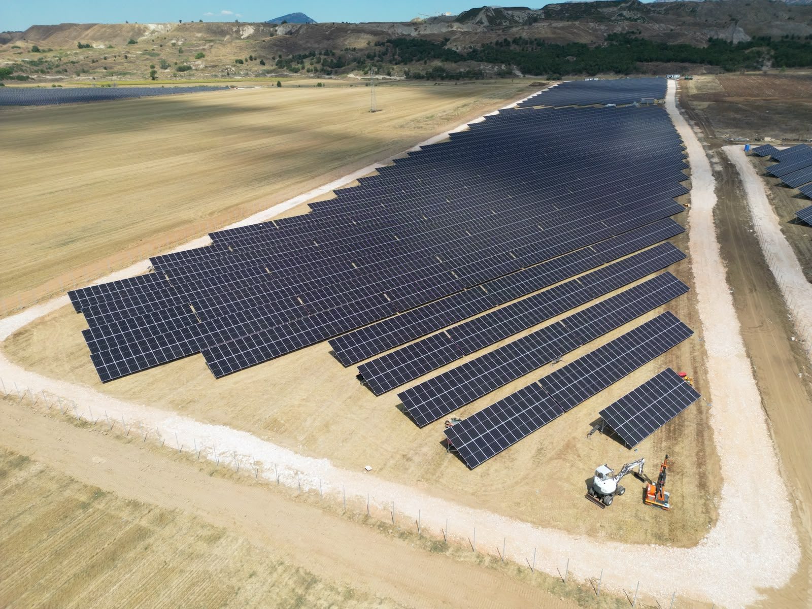 Panel rows under installation at a Novaci 3 sub-site, with mounting equipment on site