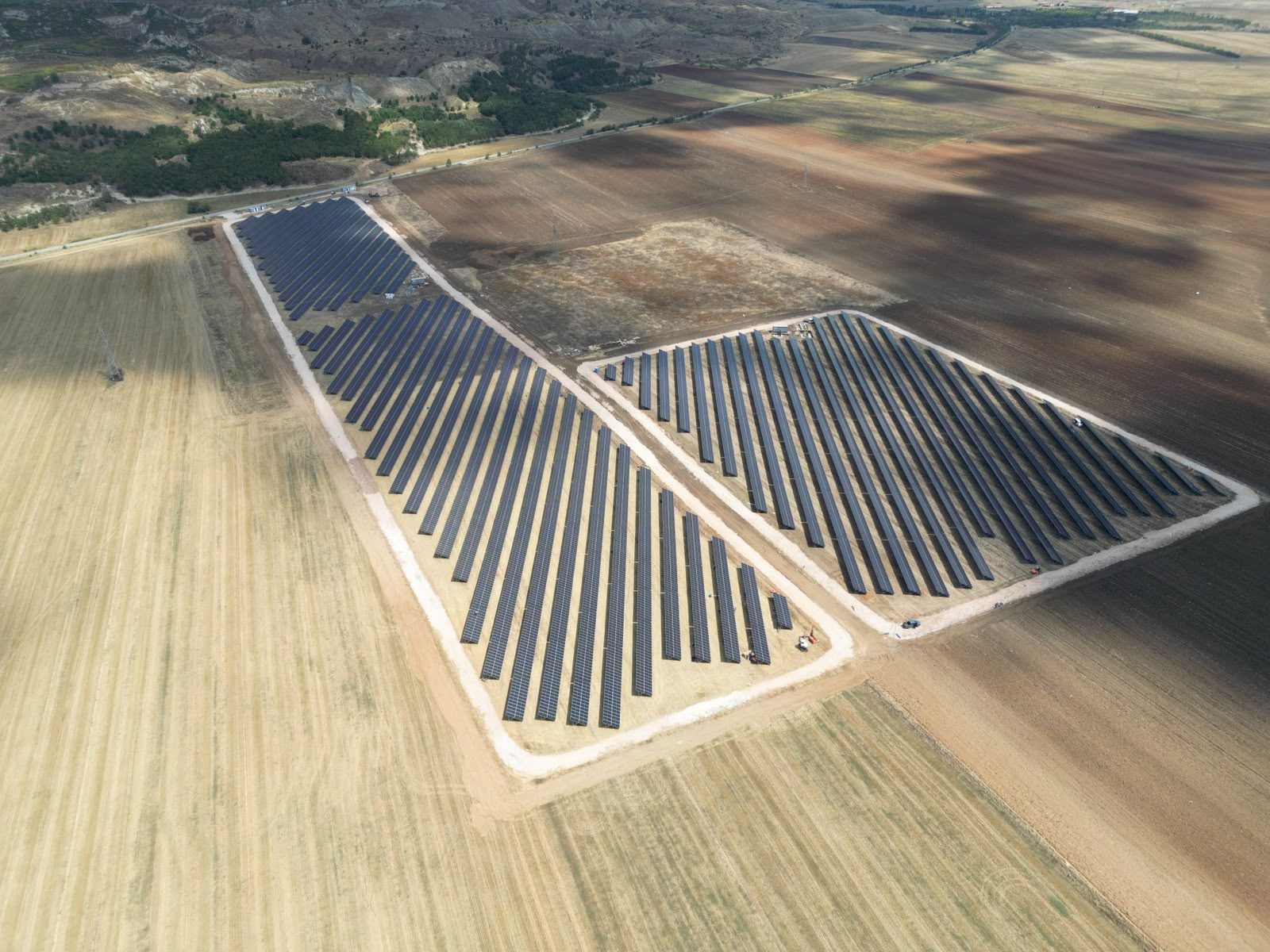 Aerial view of two Novaci 3 sub-sites, panel rows laid out between farmland and the hills